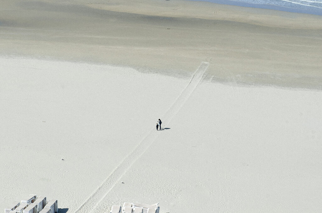Foto van hoog van 2 mensen op leeg strand met mooi lijnen spel.