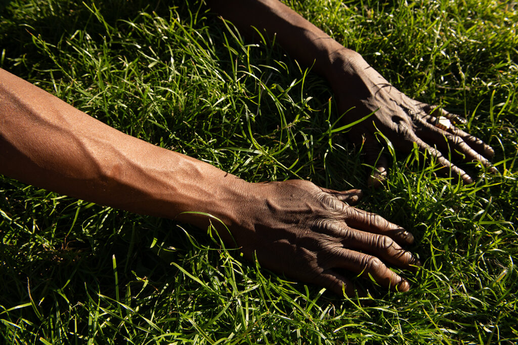 Foto van handen in park van dakloze man in het gras. Straatfotografie.